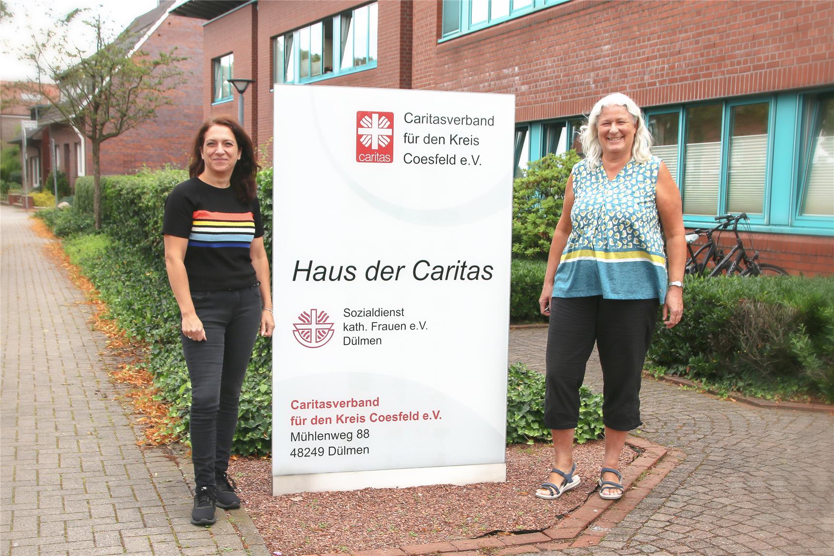 Zwei Frauen stehen neben einem Plakat des SkFs Dülmen.