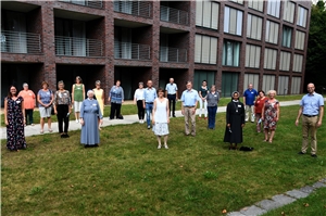 087-2020_Seelsorgliche-Begleitung Viele Menschen stehen auf einer Grünfläche vor einem Gebäude.