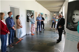 093-2020_Ausstellung_Schau-mich-an Mehrere Personen stehten in einem Flur und hören zu, wie Domkapitular Leenders die Austellung eröffnet.