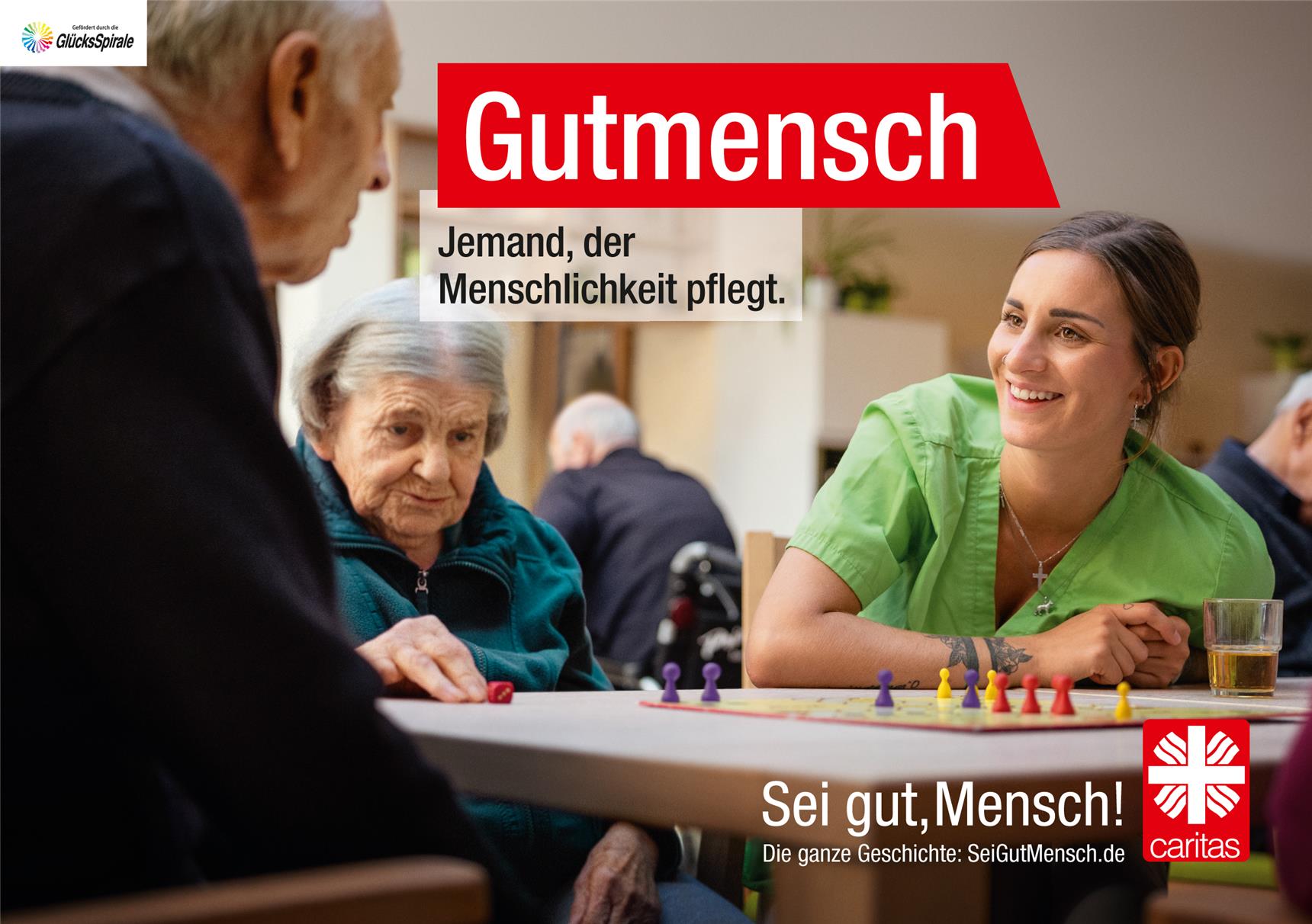 Zwei ältere Menschen und eine Pflegerin sitzen an einem Tisch und spielen das Spiel 