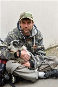 017-2022 Benefizkonzert Das Foto zeigt einen Obdachlosen mit Hund, der auf der Straße sitzt.
