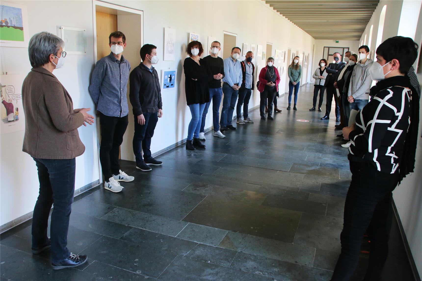 Das Foto zeigt eine Gruppe von Menschen, die locker in einem weiteren Flur zusammenstehen.