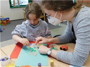 028-2021 Heilpädagogische Einrichtungen Das Foto zeigt eine Frau, die an einem Tisch mit einem Kind spielt.