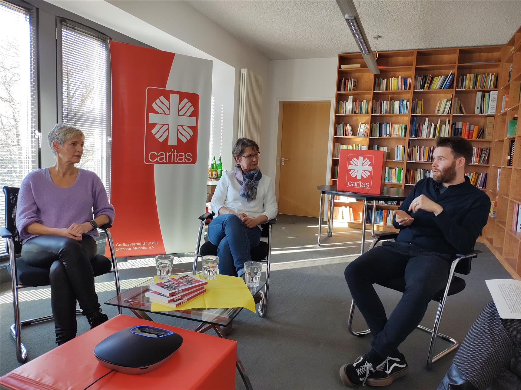 Das Foto zeigt zwei Frauen und einen Mann, die miteinander in einem Raum diskutieren.