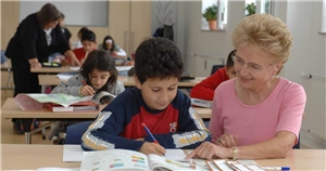 059-2021_F&A-Session_Jugendhilfe Das Foto zeigt eine ältere Frau, die einem Kind Nachhilfeunterricht gibt.