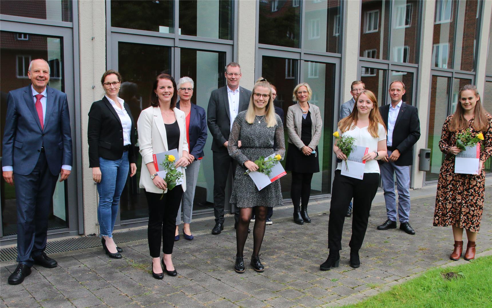 Das Foto zeigt eine Gruppe von Menschen, die vor einem Gebäude steht.
