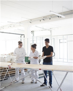 113-2021 Arbeitslosenreport Dezember Das Foto zeigt drei junge Erwachsene an einem Tapeziertisch.