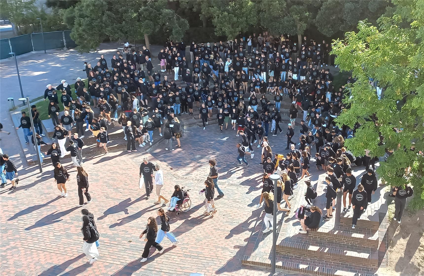Kinder auf dem Schulhof tragen schwarze Pullover mit dem Schullogo 