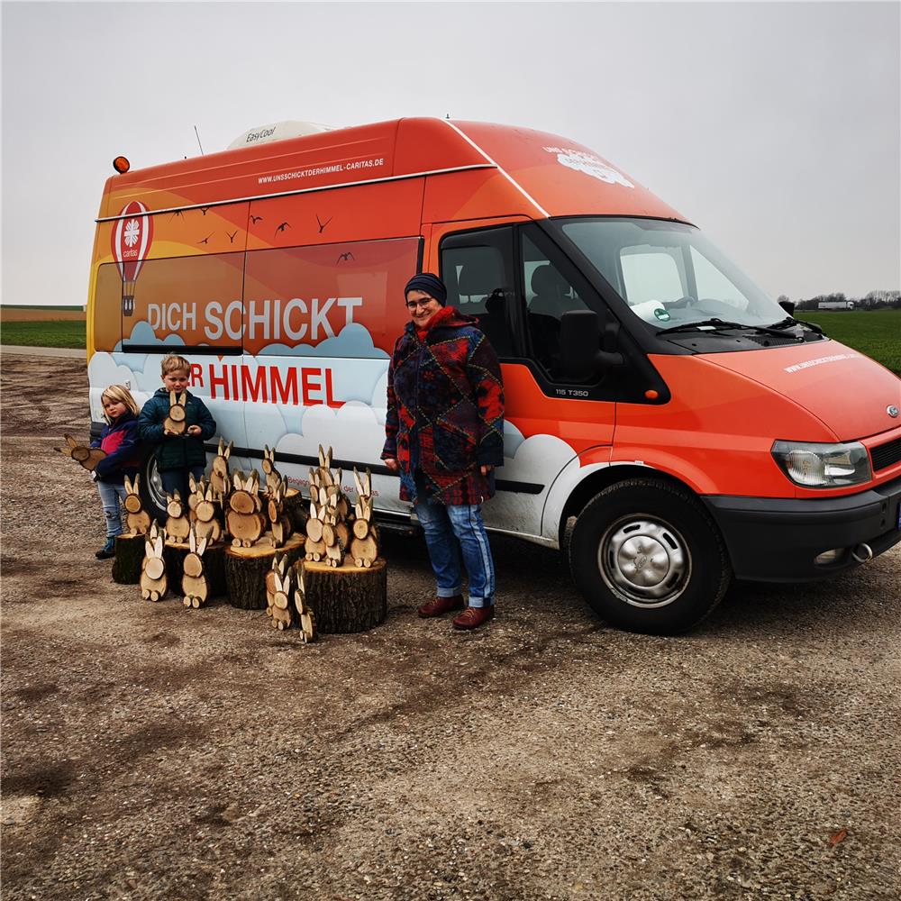 Das Foto zeigt eine Gruppe von Menschen vor einem bunt gestalteten Kleintransporter