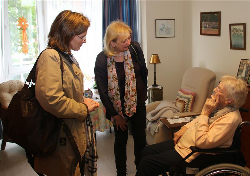 Zwei Frauen sprechen mit einer älteren Dame im Rollstuhl