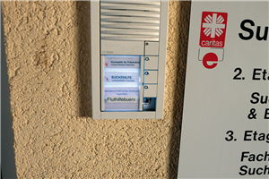 Türklingel an einem Gebäude der Caritas Euskirchen Eine Türklingel an einem Gebäude der Caritas Euskirchen, neben der ein Eingangsschild hängt. Unter den Namen der drei dort ansässigen Einrichtungen wurde die Aufschrift 'Fluthilfebüro' geklebt.