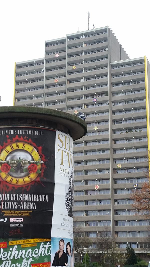 Ein Plattenbau im Stadtteil Köln-Chorweiler, vor dem einen Litfaßsäule steht