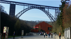 Müngstener Brücke und Haus Müngsten Das Haus Müngsten und die Müngstener Brücke in Solingen in der Frontansicht. Im Vordergrund ist ein Fußweg mit einigen Menschen zu sehen.