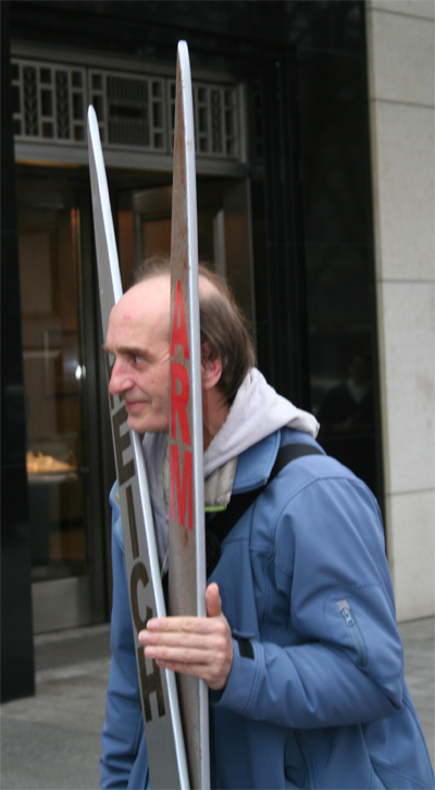 Ein Mann während einer Aktion von Caritas/Nationalen Armutskonferenz auf der Königsallee in D'dorf. Er hält seinen Kopf zwischen eine riesige Holzschere mit der Beschriftung Arm und Reich.