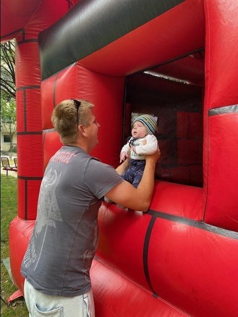 Vater mit Baby vor Hüpfburg