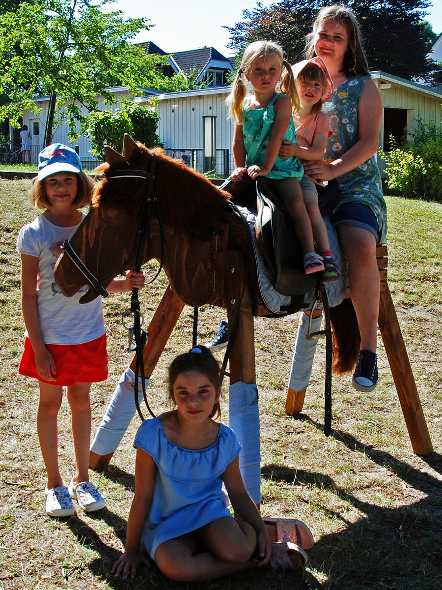 Holzpferd Elly mit spielenden Kindern