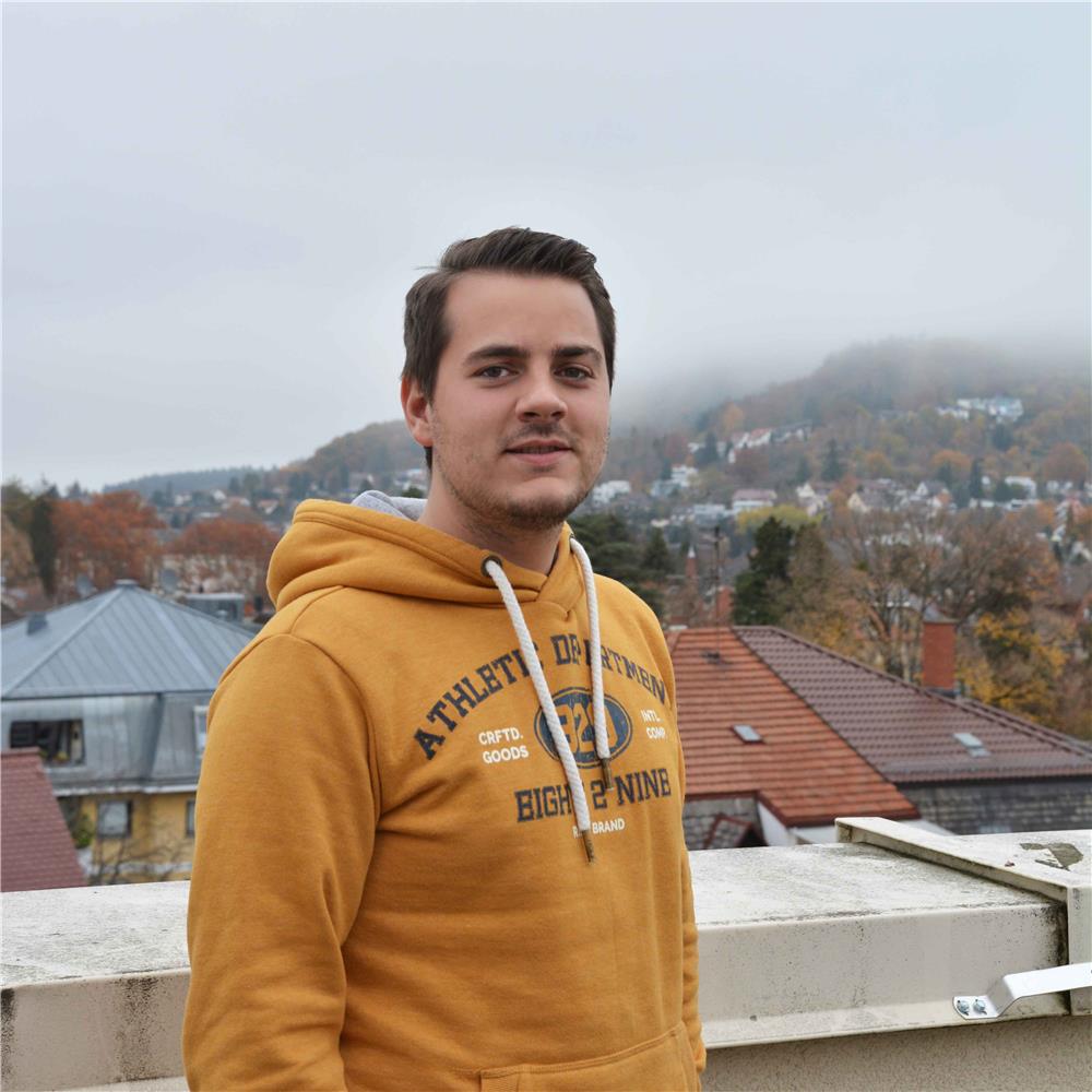 Eine junger Mann mit orangem Pullover