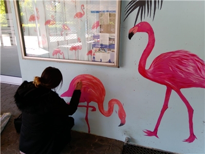 Dormagen_Raiyda beim malen Junge Frau malt an eine Hauswand zwei pinke Flamingos.