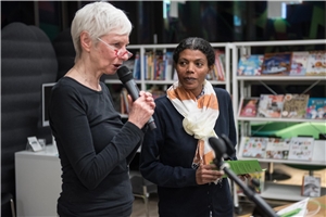 Fürth_Martha_Frauen_zusammen_sind_immer_stark Eine ältere Dame mit weißen Haaren spricht in ein Mikrofon. Neben ihr steht eine dunkelhäutige Frau.