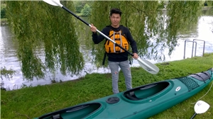 Hamburg_Ramazaan Paddelt Ein Junge mit einem Paddel in der Hand steht vor einem Kajak