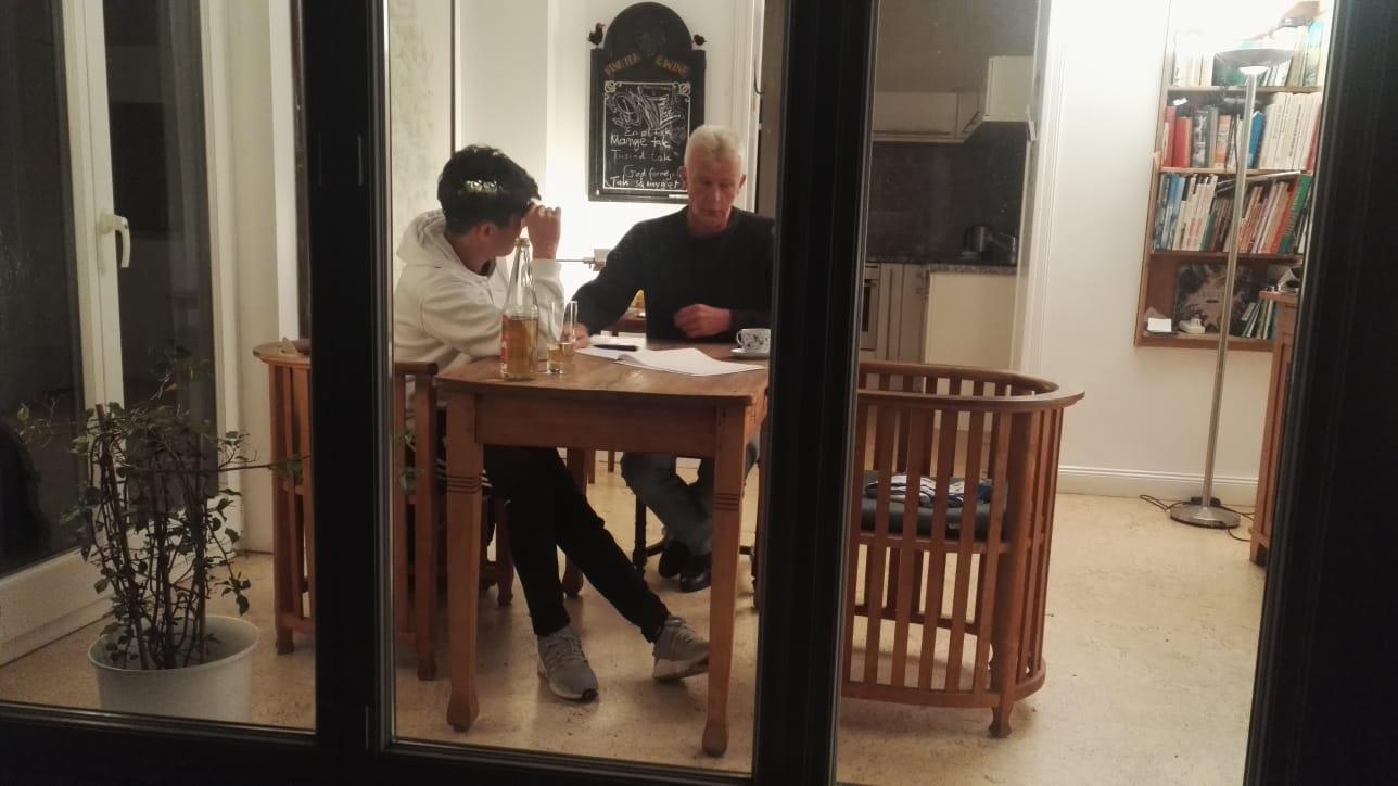 Ein Junge und ein Mann sitzen an einem Tisch.