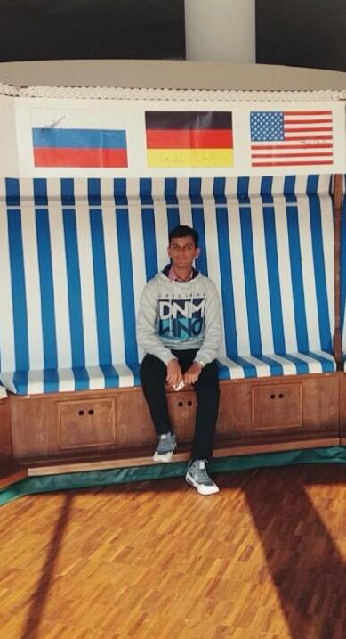 Junger Mann sitzt auf einem Sofa.