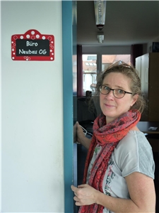 Ausbildung Heilerziehungspflege Frau mit langen braunen Haaren und Brille lehnt an Türrahmen.