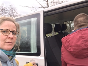 Ausbildung Heilerziehungspflege Frau mit Brille unterstützt jungen Mann beim einsteigen in einen Bus.