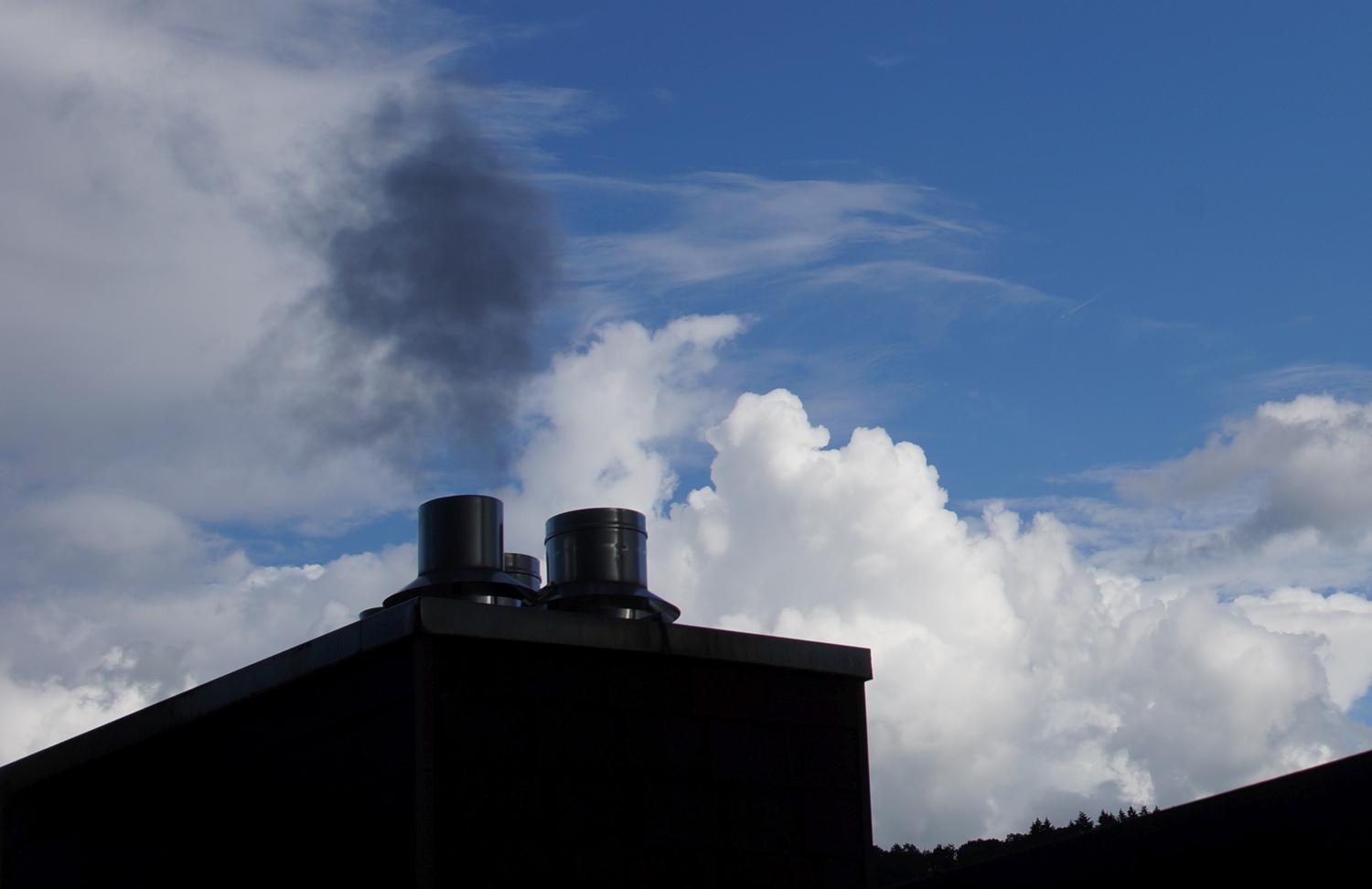 Ein Schornstein bläst Abgas in die Wolken des Himmels.