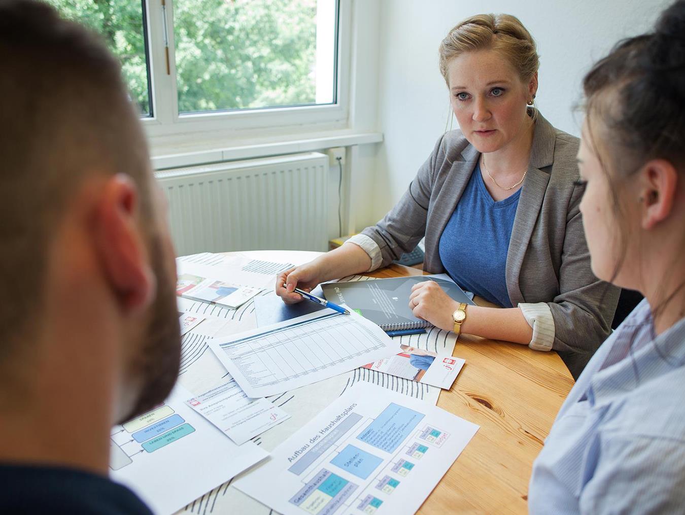 Drei Menschen sitzen am Tisch in einer Caritas-Beratungsstelle