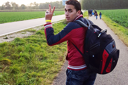 Ein junger Mann mit Rucksack auf einer Straße.