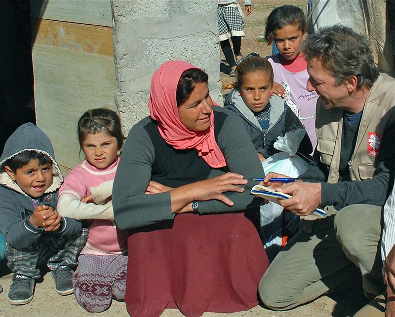 Caritasmitarbeiter im Gespräch mit Flüchtlingen im Ausland