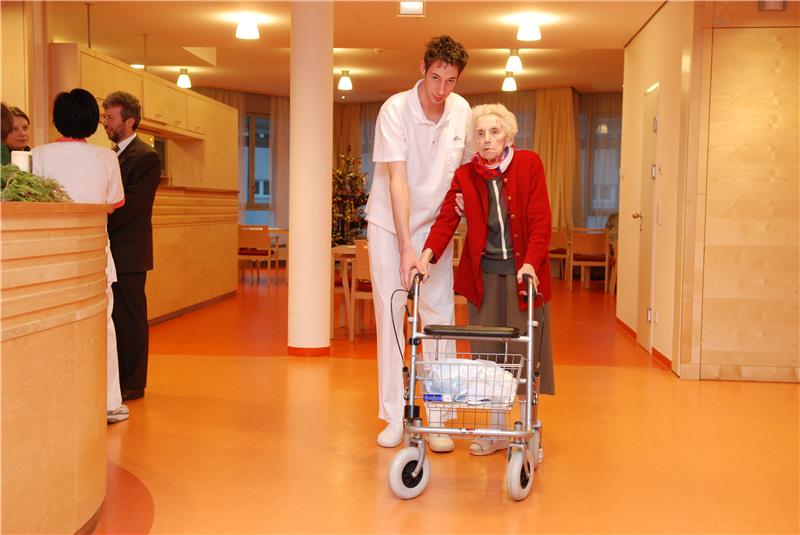 Pfleger Hilft alter Dame im  Heim über den Flur