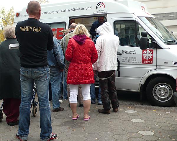 Menschen warten vor Caritas-Bus