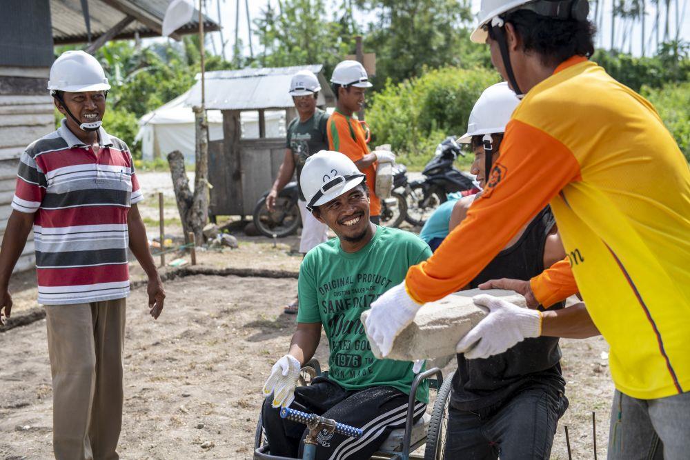 Einige Männer auf Sulawesi bauen gemeinsam an einem Haus für einen Freund im Rollstuhl.