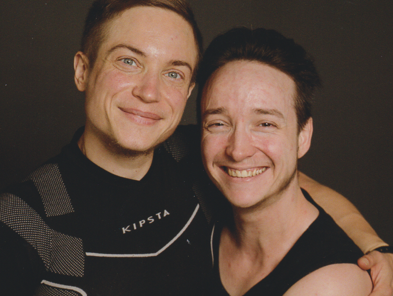 Zwei junge Männer, die sich umarmen und in die Kamera lächeln