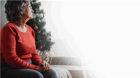 nc 22_2022 Einsamkeit Eine ältere Dame blickt neben einem geschmückten Christbaum enttäuscht ins Leere.