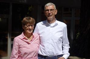 Eine Frau in einem längsgestreiften Hemd neben einen Mann in einem weißen Hemd.