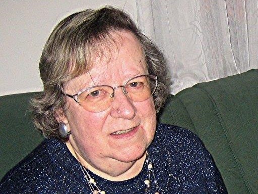 Portrait einer älteren Dame mit Brille und in dunkler Bluse.