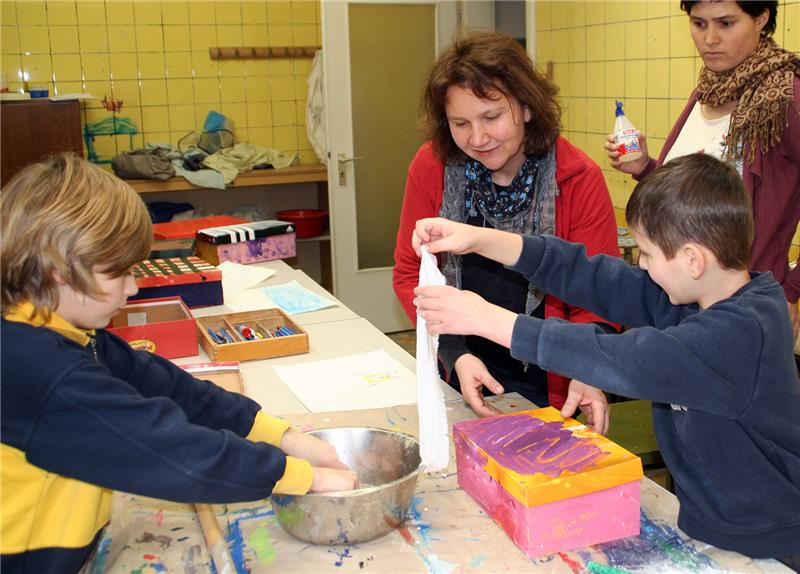 Frau mit zwei Jungen am Tisch beim Werken