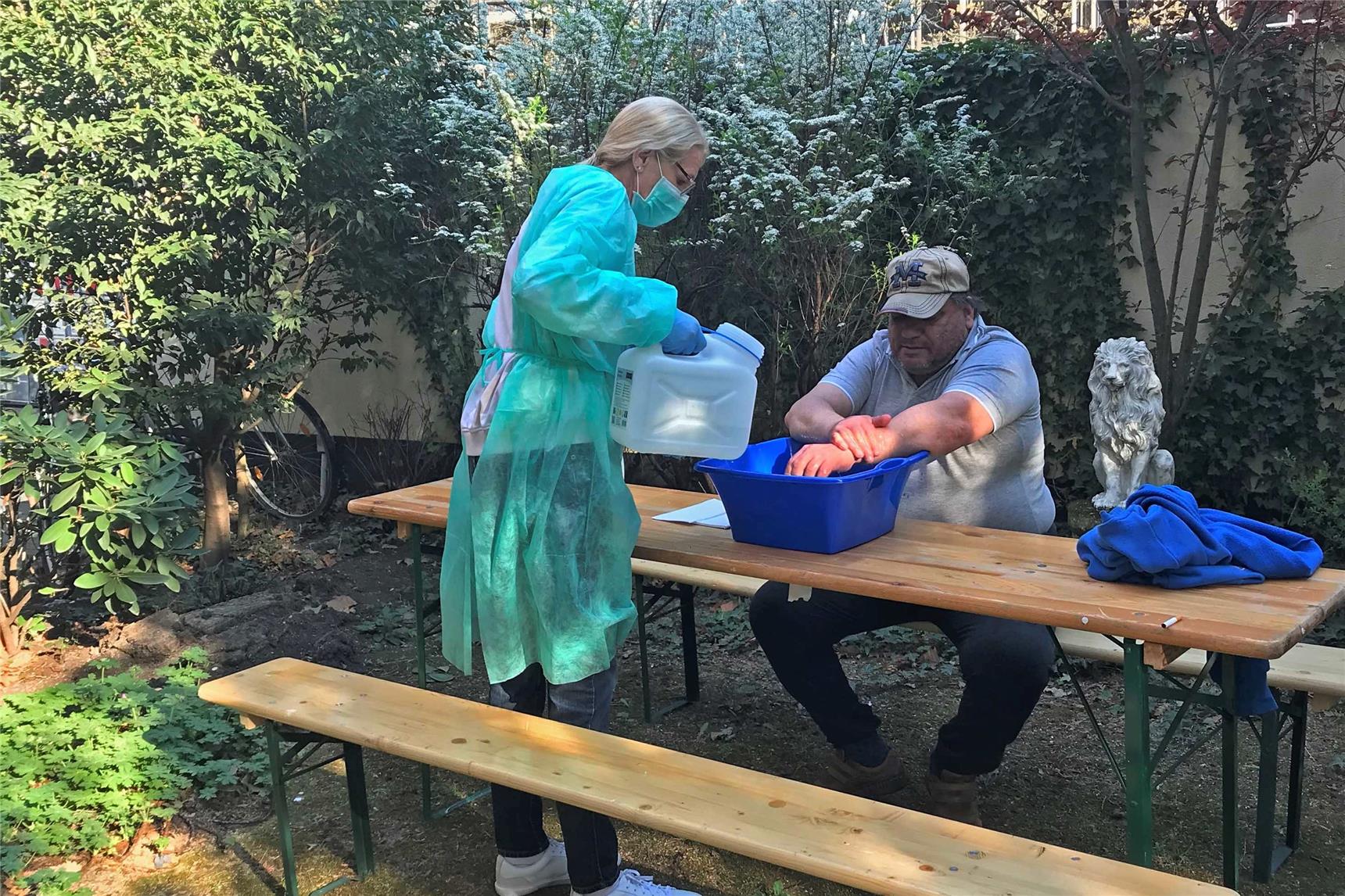 Mann wäscht sich an einer mobilen Waschgelegenheit die Hände.