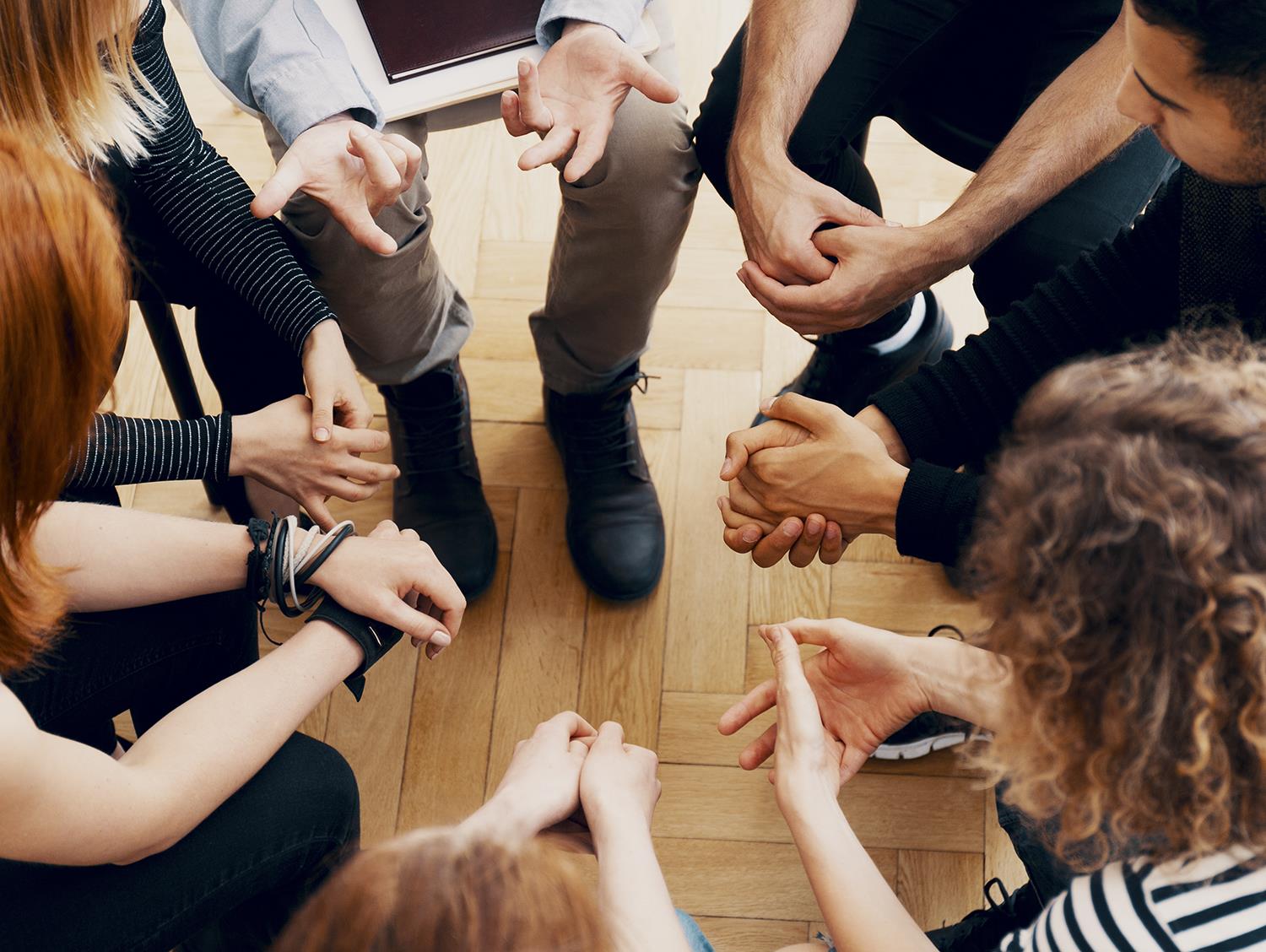 Junge Leute sitzen in einem Kreis und tauschen sich aus 