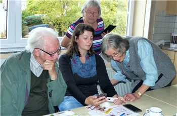 Smartphone-Sprechstunde Gruppe Eine Seniorengruppe lässt sich von einer jungen Frau den Umgang mit Smartphones erklären.