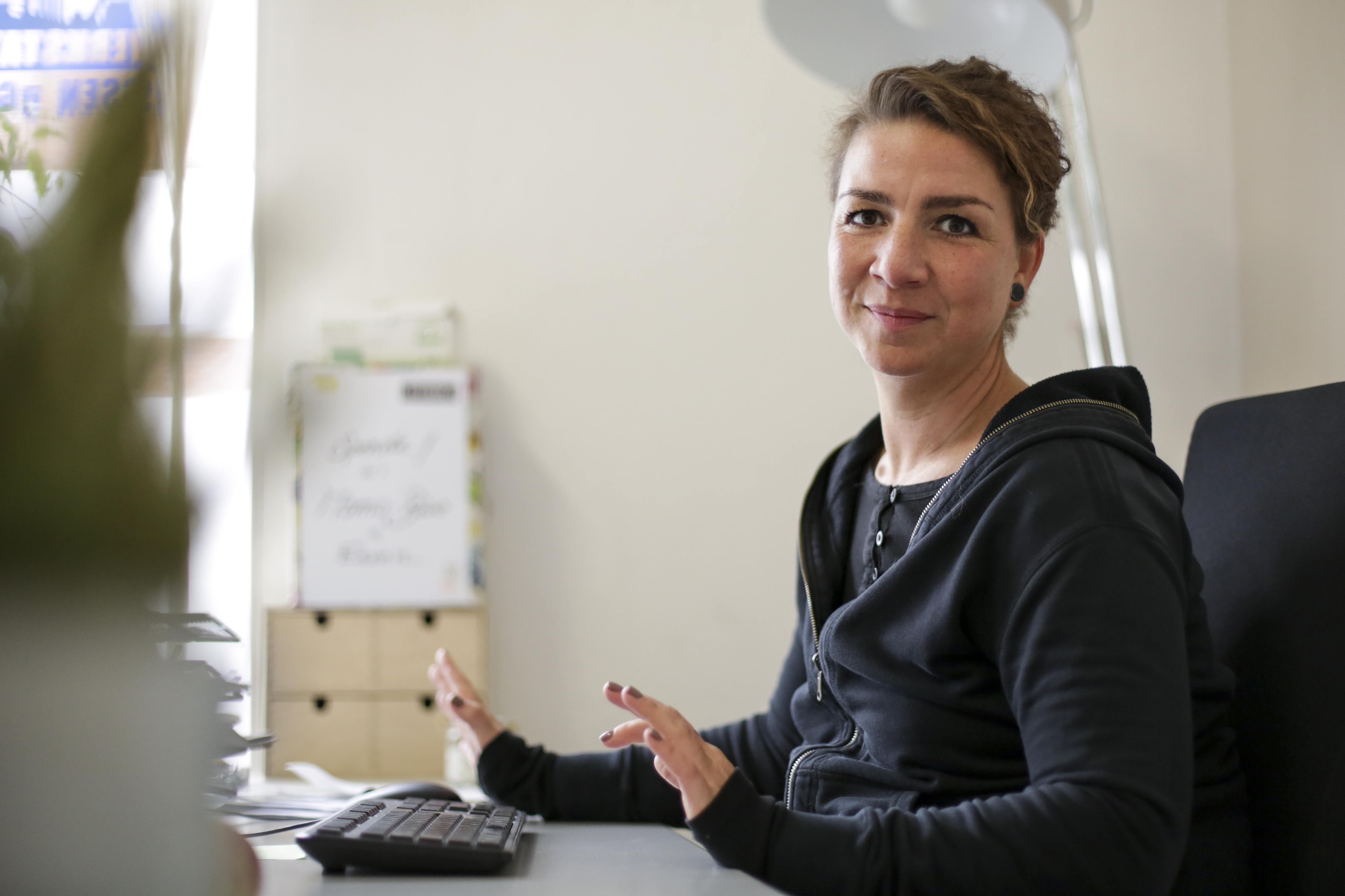 Eine Frau in schwarzer Kleidung sitzt vor einer Tastatur.