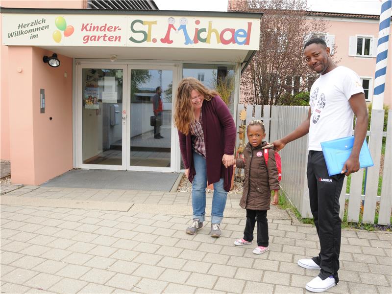 Flüchtlingskind mit Vater und Ehrenamtlicher vor Kindergarten