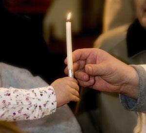 kleine Hand übergibt Kerze in große Hand