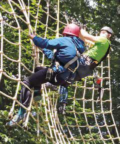 Zwei Jugendliche klettern an einem Netz.
