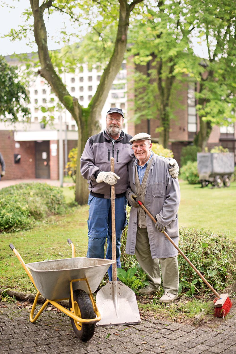 Zwei ältere Herren mit  Schubkarre, Schaufel und Besen