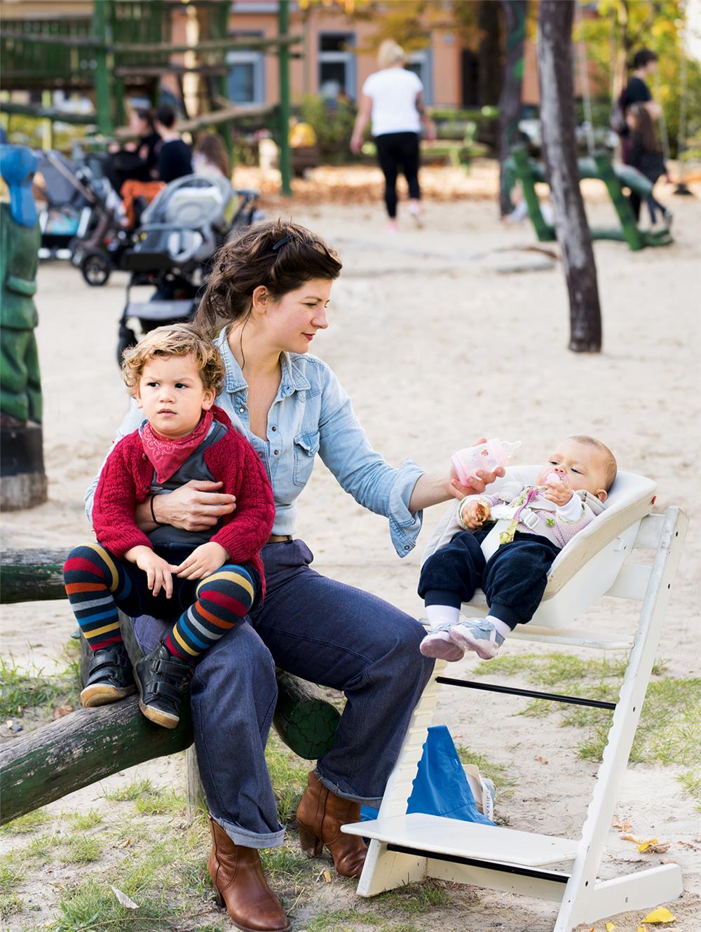 Frau hält ein Kind auf dem Arm und füttert ihr Baby