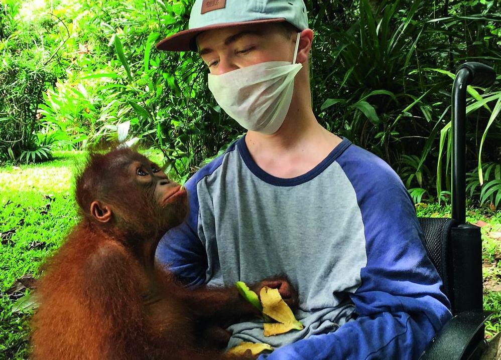 Benni Over, im Rollstuhl, hält Orang-Utan Mona auf dem Schoß.